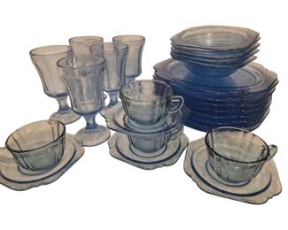 2720 - 26pc Blue Madrid Depression Glass Set (Description): A 26-piece Blue Madrid depression glass  collection featuring an assortment of  dinnerware pieces. The set includes footed  goblets, cups with matching square saucers,  dinner plates, and bowls, all in the iconic pale blue Madrid pattern with its  characteristic floral and geometric pressed  glass design. This Federal Glass Company  pattern showcases the elegant scalloped edges  and embossed motifs typical of 1930s