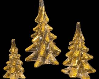 2791 - 3 Gold Flecked Art Glass Christmas Trees 6" (Description): Set of three art glass Christmas tree  figurines featuring gold flecking throughout  clear glass. The graduated set includes trees  in three sizes, with the tallest measuring 6  inches. Each tree displays a tiered, stylized design with a pointed top, creating  an elegant holiday display piece.