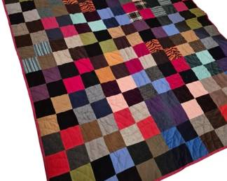 3763 - Handmade Patchwork Quilt 75"x58" (Description): Handmade patchwork quilt featuring a colorful  grid pattern of square fabric patches in  various colors, textures, and patterns  including solids, plaids, stripes, and  prints. The quilt displays a rich mix of earth tones, jewel tones, and neutral shades  with red binding along the edges.  Hand-quilted with visible stitching  throughout.