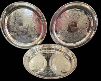 523 - 3 Rogers Silver Plated Serving Trays Trio 15" (Description): A collection of three Rogers silver plated  serving trays featuring ornate engraved  floral and scroll designs on their surfaces.  The group includes two round trays with  decorative gadroon and beaded rim edges, and one oval gallery tray with a pierced  reticulated border. Each tray displays the  characteristic bright-cut chased patterns  popular in traditional silver plate serving  pieces. The largest measures 15 inches.