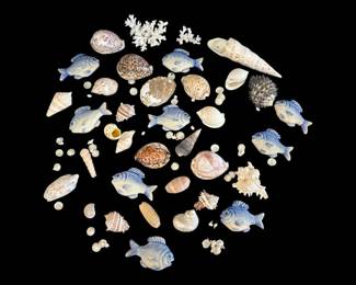 529 - Group Lot of Seashells & Porcelain Fish (Description): A charming collection of natural seashells  and decorative porcelain fish figurines. The  lot includes an assortment of various shell  specimens in different sizes, shapes, and  patterns, including cowrie shells, conch shells, spiral shells, and coral pieces. The  porcelain fish are glazed in soft blue tones  with hand-painted detail work. A delightful  grouping suitable for coastal decor,  crafting, or display.