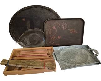 4041 - Group Lot of Assorted Decorative Trays (Description): A group lot of assorted trays in various  styles and materials. The collection includes  a large round dark tray with studded border,  a rectangular tray with painted floral  motif, two clear glass fish-shaped platters, a galvanized metal serving tray with handles,  and a wooden tray containing bamboo  placemats and natural materials.