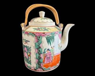539 - Rose Medallion Porcelain Teapot 8"x8" (Description): Rose Medallion porcelain teapot featuring  traditional hand-painted decoration with  figural court scenes, floral panels with  birds and butterflies, and characteristic  pink, green, and orange enameling. The teapot has a fitted domed lid with finial and a  woven rattan overhead handle. Measures 8  inches by 8 inches.
