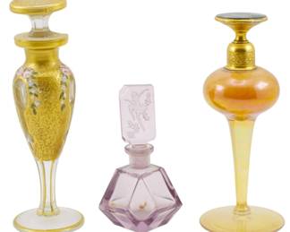 178 - 3 Vintage Perfume Bottles (Description): A collection of three vintage perfume  bottles. The lot includes a gold-decorated  bottle with floral enamel accents, a faceted  amethyst-colored bottle with a figural  stopper, and an iridescent amber bottle with a gilt metal top.