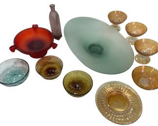 951 - Mid-Century Glass Collection (Description): A collection of mid-century glass pieces  featuring an assortment of colored glassware.  The lot includes a large frosted green oval  centerpiece bowl, a vibrant red-orange  handled dish, a frosted lavender bottle vase, several amber and marigold carnival glass  sherbet cups on clear pedestals, coordinating  iridescent marigold plates, and hand-blown  bubble glass bowls in aqua and amber tones. A  versatile grouping showcasing various