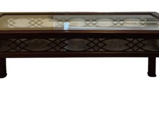312 - Showcase Coffee Table 40"x48"x23" (Description): Showcase coffee table featuring a glass top  inset within a dark wood frame. The table  displays elegant Chippendale-style fretwork  along the apron and corner brackets on the  square legs. The glass top allows for display of items beneath.