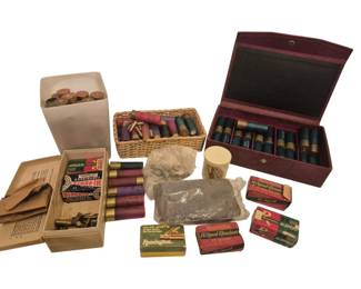 2724 - Group of Vintage Ammunition and Boxes (Description): A collection of vintage ammunition and  ammunition boxes, mostly full. The lot  includes various shotgun shells in assorted  colors housed in a burgundy leather case, a  wicker basket, and a ceramic container. Also included are several vintage cardboard  ammunition boxes from brands including  Remington Hi-Speed Kleanbore, Yellow Jacket,  and Hi-Power. Additional loose cartridges and  brass casings are present throughout the