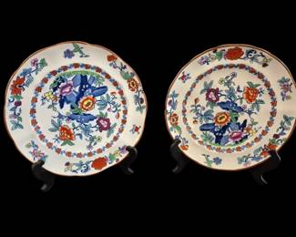 489 - 2 Booths China Plates Floral Pattern 9" (Description): Pair of Booths china plates featuring a  vibrant floral pattern in the Imari style.  Each plate displays a central design with  blue rockwork and colorful flowers including  peonies and chrysanthemums in shades of red, orange, pink, blue, and green. The plates  feature a decorative border with floral  garland motifs and an orange-brown rim edge.  Each plate measures 9 inches in diameter.