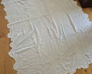 1312 - White Eyelet Embroidered Cotton Bedspread (Description): White cotton bedspread featuring delicate  eyelet embroidery with floral motifs  throughout. The spread has a scalloped edge  border with intricate cutwork detailing.  Measures 87 inches by 69 inches.