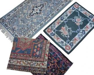 2804 - Group of Four Decorative Area Rugs (Description): A group of four decorative area rugs in  various styles and sizes. The collection  includes a light blue Persian-style runner  with central medallion and fringe, a green  floral hooked rug with rose motifs, a geometric tribal-style rug in blue and red  tones, and a dark floral patterned rug in  deep burgundy and navy hues. Each rug  features traditional designs suitable for  accent use throughout the home.
