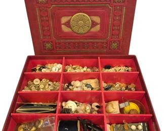 1455 - Vtg Red Leather-Look Box Full of Buttons (Description): A vintage red box filled with an extensive  collection of assorted buttons. The  decorative box features an embossed lid with  gold tooling in a classical design including  a central medallion and ornate corner motifs. The interior is divided into compartments  containing hundreds of buttons in various  materials including mother of pearl, bone,  shell, and plastic in assorted sizes and  colors. Also includes sewing notions such as