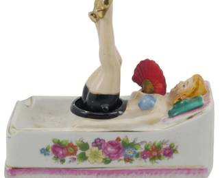1873 - Vtg Pin Up Girl "Naughty Noodler" Ashtray (Description): Vintage Pin Up Girl "Naughty Noodler" ashtray  figure. This novelty ceramic piece features  a reclining pin-up figure with colorful  floral decoration on the base. Measures 5.5"  x 6" x 3".