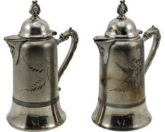 160 - 2 Vtg Quadruple Plate Coffee Pots 7" (Description): Two vintage quadruple plate coffee pots  featuring engraved floral and foliate designs  on the bodies. Each pot has a domed lid with  decorative finial, an ornate scrolled  handle, and a covered spout. The pots measure 7" in height.