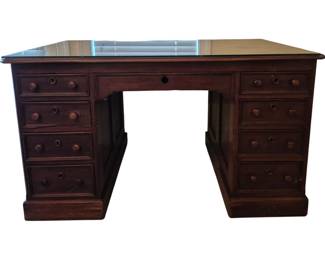 3805 - Victorian Walnut 9-Drawer Desk 31.5"x54"x32" (Description): Victorian walnut nine-drawer desk featuring a  double pedestal design with four drawers on  each side and a center drawer. The desk  showcases turned wooden knobs throughout and  rests on a plinth base. The top is fitted with a protective glass surface.