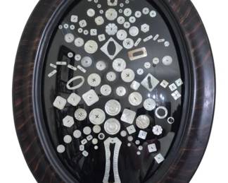 1268 - Oval Bubble Glass Frame of Button Collection (Description): A vintage collection of mother of pearl  buttons and buckles artistically arranged in  a tree or floral design, displayed against a  black background within an oval convex glass  frame. The frame features a tiger stripe or faux tortoise shell finish. This decorative  piece, known as Bible Glasses from Quilt,  showcases an assortment of antique mother of  pearl buttons in various shapes including  round, square, rectangular, and decorative