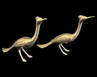 536 - Pr Brass Buffet Birds As Is Broken Beak 8" (Description): Pair of brass buffet birds featuring elegant  long-necked bird figures with decorative  feather detailing and crested heads. These  mid-century style decorative birds stand on  splayed feet in a striding pose. Sold as is with broken beak. Measures 8 inches.