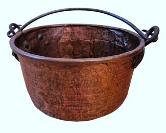 603 - Hammered Copper Cauldron w/ Iron Handle (Description): Antique hammered copper cauldron or bucket  featuring decorative punched dot pattern  bands around the body. The vessel is fitted  with a wrought iron swing handle with looped  terminals. The copper shows a beautiful aged patina consistent with age and use. This  style of copper cauldron was traditionally  used for cooking over open hearths. Measures  11" x 20".