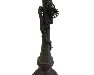 402 - Japanese Meiji Bronze Candlestick w/ Dragon (Description): Japanese Meiji period design bronze  candlestick holder featuring a sculptural  dragon coiled around the central column. The  piece displays intricate detailing  throughout, with the dragon depicted in a dynamic climbing pose with extended claws and  flowing mane. The candlestick has a  scalloped lotus-form bobeche at the top. The  bronze exhibits a rich dark patina consistent  with age. Measures 14.5" tall.