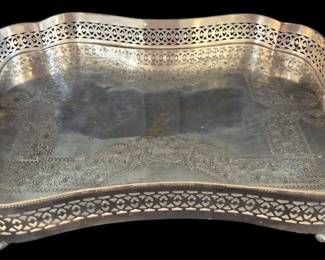 506 - Silver Plate Reticulated Tray w/ Handles (Description): Silver plated reticulated gallery tray  featuring an elegant serpentine form with  pierced lattice gallery edges. The tray  surface displays elaborate Victorian-style  chased and engraved decoration with floral scrollwork and cartouche designs in the  corners. Fitted with two integrated cut-out  handles for easy carrying. The tray rests on  four ball feet. Measures 19" x 14.5".
