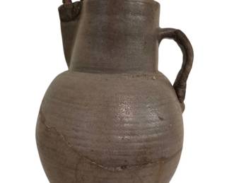 3794 - Stoneware Pitcher w/ Pussy Willows w/ Crack (Description): Rustic gray stoneware pitcher with a single  curved handle, displaying the characteristic  texture of hand-thrown pottery. The vessel  features a rounded bulbous body tapering to a  cylindrical neck. There is a visible crack in the piece. Currently filled with dried  pussy willow branches. Pitcher measures 13" x  9".