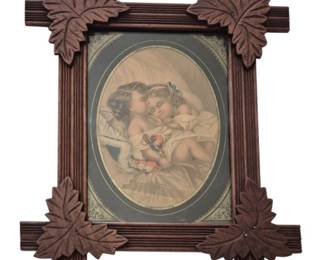 1275 - Ant. Black Forest Style Frame w/ Print 17x15 (Description): Antique Black Forest style carved wooden  frame featuring decorative leaf motifs at  each corner. The crossed corner construction  with reeded molding is characteristic of the  Victorian era. The frame houses an oval-matted chromolithograph print depicting  two cherubic children in a tender embrace.  Measures 14 inches by 11 inches.