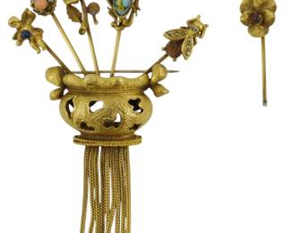 1910 - Coro Stickpin Holder Brooch w/ Stickpins (Description): Coro stickpin holder brooch featuring a  decorative vase-form holder with chain fringe  tassels. The brooch holds multiple  ornamental stickpins with various decorative  tops. One stickpin has broken off from the holder.