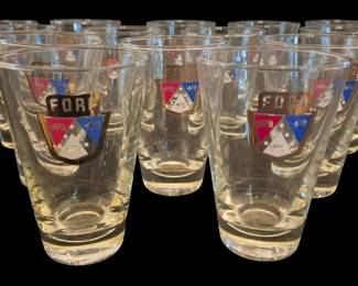 2785 - 14 Ford Tumblers 5" (Description): Set of fourteen vintage Ford tumblers, each  measuring 5 inches tall. The clear glass  tumblers feature a colorful Ford crest logo  with red, blue, and gold enamel detailing and  the Ford name in gold lettering. A classic piece of automotive memorabilia perfect for  collectors.
