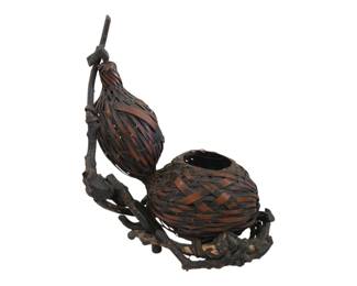 403 - Antique Japanese Ikebana Gourd Basket (Description): Antique Japanese Ikebana basket featuring a  distinctive double gourd form with woven  bamboo construction. The basket is crafted  with intricately woven bamboo strips in warm  brown tones, mounted on a naturalistic gnarled root wood base that provides organic  sculptural appeal. The design includes a  taller elongated gourd shape alongside a  rounded vessel opening, connected by the  rustic branch framework. This traditional