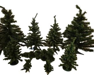 4082 - Group of 9 Small Artificial Christmas Trees (Description): A group of nine small artificial Christmas  trees. The collection features tabletop-sized  evergreen trees in varying heights and  styles, each with green plastic bases. The  trees display traditional pine needle construction suitable for holiday decorating  or display purposes.