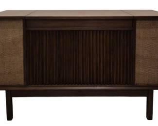 3974 - Motorola Mid Century Record Stereo Console (Description): Motorola Mid Century record stereo console  model SK111W in working condition. This  vintage stereo features a walnut-toned wood  cabinet with classic mid-century modern  design, including a slatted front panel and woven speaker grilles on either side. The  console stands on tapered legs and has a  lift-top lid for turntable access. Used as is electric/electronic/mechanical  item. No guarantee all components, untested.