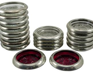 119 - 19 Silver Plate & Glass Bottle Coasters (Description): A collection of nineteen silver plate and  glass bottle coasters. The set includes  coasters with clear glass inserts as well as  examples featuring ruby red glass centers.  Each coaster is finished with a decorative beaded rim in silver plate.