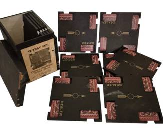 4012 - 12 Paine's Duplicate Whist Trays (Description): Complete 12-tray set of Paine's Duplicate  Whist Trays in original storage box. The  trays feature a black background with  decorative red and pink ornamental corner  designs. Each tray is marked with 'DEALER' text and directional arrows for proper card  game organization. The storage box displays  the original '12-Tray Set' label identifying  these as Paine's Duplicate Whist Trays. A  classic card game accessory from the era when