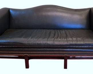 607 - Hancock & Moore Leather Camelback Sofa (Description): A classic Chippendale-style camelback sofa  upholstered in leather with brass nailhead  trim detailing along the rolled arms and  base. The sofa features a single loose  cushion seat and rests on a mahogany-finished stretcher base with straight legs. Measures  35 inches high by 82 inches wide by 34 inches  deep.