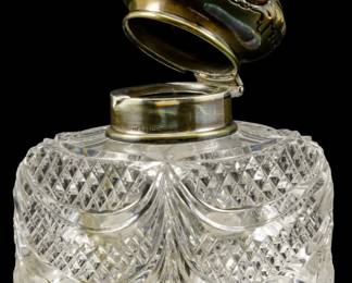 130 - Harris & Shafer Sterling & Crystal Inkwell (Description): Harris & Shafer sterling lidded crystal  inkwell featuring an ornate repousse silver  lid mounted on a cut crystal base. Measures  4".