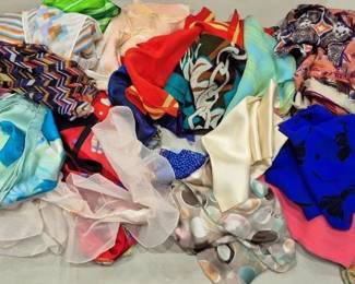 2849 - Lot of Assorted Scarves (Description): A collection of assorted scarves featuring a  variety of colors, patterns, and materials.  The lot includes silk and synthetic scarves  in geometric, floral, abstract, and solid  designs. Colors range from vibrant reds, blues, and teals to softer pastels and earth  tones. Various sizes and styles are  represented, including square and oblong  shapes suitable for diverse styling options.