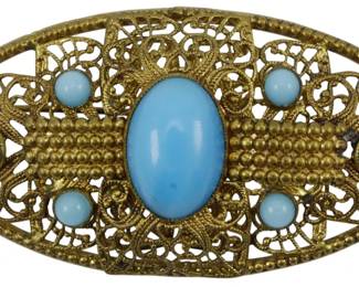 1909 - Czechoslovakia Turquoise Glass Brooch (Description): A turquoise glass brooch made in  Czechoslovakia. The piece features  turquoise-colored glass stones set in an  ornate gold-toned filigree setting.
