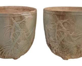 4047 - 2 McCoy Planters w/ Pine Cone Relief 7"x8" (Description): Pair of McCoy planters featuring raised pine  cone and branch relief decoration. The  planters display a soft sage green glaze with  natural terracotta tones visible at the rims  and bases, giving them a weathered, rustic appearance. Each planter measures 7 inches by  8 inches.