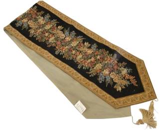 354 - Floral Tapestry Table Runner w/ Tassels (Description): A decorative tapestry table runner featuring  a floral design on a dark background with an  ornate gold-toned border. The runner is  finished with decorative tassels at the ends  and includes a fabric backing. Measures 70 inches long by 12.75 inches wide