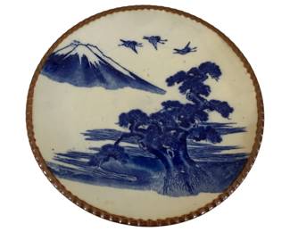 298 - Blue & White Japanese Mt. Fuji Charger 12.5" (Description): Blue and white decorative plate featuring a  traditional Japanese scene with Mount Fuji in  the background, a gnarled pine tree in the  foreground, and cranes in flight. The charger  has a brown scalloped rim edge. Measures 12.5 inches in diameter.