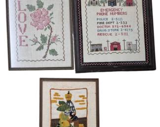 4121 - 3 Framed Needlepoints 19"x15" (Description): Collection of three framed needlepoints  measuring 19 by 15 inches. The grouping  includes a romantic "LOVE" design featuring a  pink rose, a charming emergency phone  numbers sampler depicting a small town with church, school, police station, fire  deprtment and hospital buildings, and a  sewing-themed piece dated January 1975  showing a dress form with sewing notions.  Each is presented in a wooden frame.