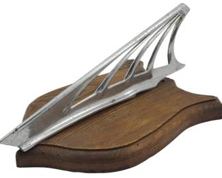 1881 - Desoto Airflow Hood Ornament (Description): Vintage Desoto Airflow original hood ornament  mounted on a wooden display base. This  authentic automobile hood ornament features  the distinctive streamlined design  characteristic of the Airflow series. Measures 5 inches by 12 inches by 7 inches.