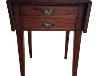 1280 - Antique Drop Leaf Side Table w/ Two Drawers (Description): Antique drop leaf side table crafted in dark  walnut or mahogany with two drawers featuring  brass oval pull hardware. The table stands  on four tapered legs in a Federal or  Hepplewhite style. The top shows natural age-related patina and wear consistent with  its age. Measures 29" x 18" (opens to 30") x  20".