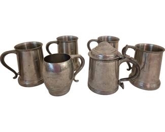 3953 - Collection of Six Pewter Beer Mugs & Tankards (Description): A collection of six metal beer mugs in pewter  or pewter-style finish. The assortment  includes five open-top tankards of varying  styles, some with elegant curved handles and  others with straight handles featuring monogrammed initials, along with one lidded  tankard with a decorative thumbpiece. The  pieces display classic English pub-style  design with banded detailing and traditional  silhouettes.