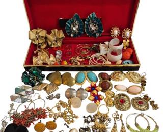 1989 - Jewelry Box w/ Costume Earring Collection (Description): A jewelry box containing a collection of  costume earrings in various styles. The  assortment includes clip-on and pierced  earrings featuring an array of designs  including gold-tone bow earrings, floral motifs, faux pearl studs, turquoise cabochon  drops, coral-style dangles, enamel flower  earrings, hoop earrings, and various beaded  and metalwork pieces. The box features a red  velvet-lined interior with a brass-tone metal