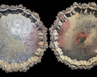 530 - 2 Sheridan Silver Plated Serving Trays 17"x17" (Description): Two Sheridan silver plated serving trays  measuring 17 inches by 17 inches. Each tray  features an ornate scalloped edge with  elaborate rococo-style shell and scroll  border decoration. The center of each tray is beautifully engraved with intricate foliate  scrollwork, acanthus leaves in cartouches,  and crosshatch patterns. The trays rest on  decorative feet. A handsome pair suitable for  formal entertaining.