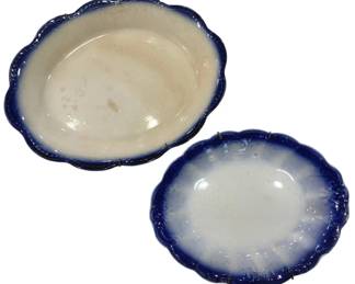 994 - 2 Antique Flow Blue Scalloped Edge Platters (Description): A pair of antique flow blue platters  featuring elegant scalloped edges. These  oval-shaped serving pieces display the  characteristic flow blue technique where the  cobalt blue decoration has bled into the white ironstone body, creating a soft,  feathered effect around the rims. The  platters show gentle age-related wear  consistent with antique pieces and retain  plate hangers on the backs.