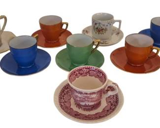 3949 - Collection of 10 Assorted Cups & Saucers (Description): A collection of 10 cups and saucers in  assorted styles and colors. The set includes  various demitasse and teacup styles featuring  solid colors with gold trim, floral  patterns, and transferware designs. Colors range from vibrant yellow, blue, green,and  orange to traditional pink and white  patterns.