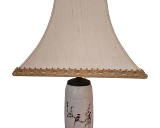 3952 - Oriental Ceramic Lamp w/ Bird Motif 32" (Description): Oriental ceramic table lamp featuring a  cylindrical white porcelain body decorated  with a hand-painted bird perched on flowering  branches. The lamp displays a Greek key  pattern border near the top and rests on a carved wooden base. Topped with a  pagoda-style cream silk shade with gold  tassel fringe trim. Measures 32 inches tall  overall. Used as is electric/electronic/mechanical