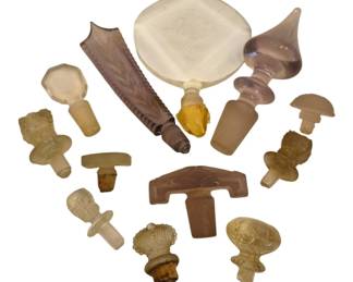 1492 - Collection of Vintage Glass Perfume Stoppers (Description): A collection of vintage glass perfume and  decanter stoppers in various styles and  sizes. The assortment includes clear,  frosted, and amethyst-tinted glass examples  featuring diverse decorative designs including faceted, mushroom-shaped, figural,  andgeometric forms. Some stoppers retain  original cork fittings. An attractive  grouping suitable for collectors or for use  as replacement stoppers.