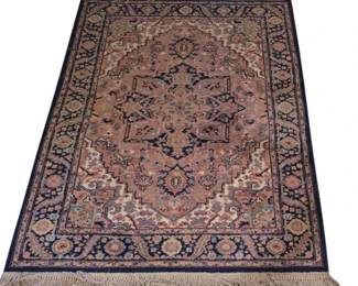 3944 - Karastan Rug 83"x52" (Description): Karastan rug featuring a traditional  Persian-style medallion design with a  rose-colored central field. The rug displays  an intricate geometric medallion surrounded  by elaborate floral and foliate motifs in shades of navy, cream, coral, and gold. A  navy blue border with repeating floral  patterns frames the piece, and fringed ends  finish both short sides. Measures 83 inches  by 52 inches.